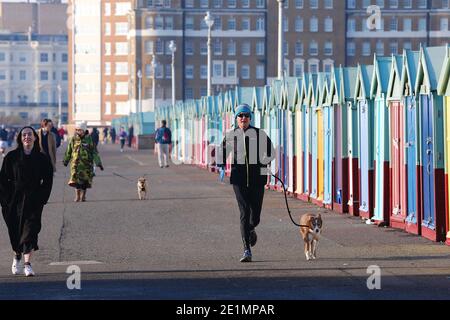 Hove, East Sussex, Großbritannien. Januar 2021, 08. UK Wetter: Ein kühler, aber heller und sonniger Tag an der Strandpromenade und am Strand als Menschenmassen nutzen einige mit Gesichtsmasken das schöne Wetter. Ein Mann joggt mit seinem Hund an der Leine. Foto-Kredit: Paul Lawrenson/Alamy Live Nachrichten Stockfoto