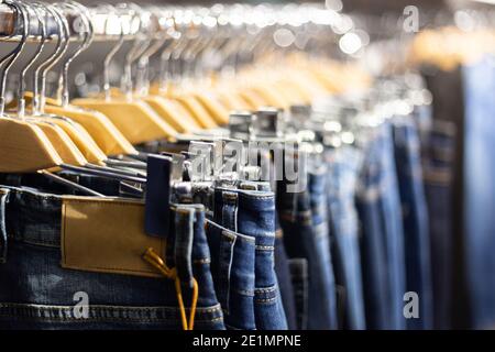 Reihe von aufgehängten blauen und schwarzen Jeans auf hölzernen Kleiderbügel in einem Geschäft. Stockfoto