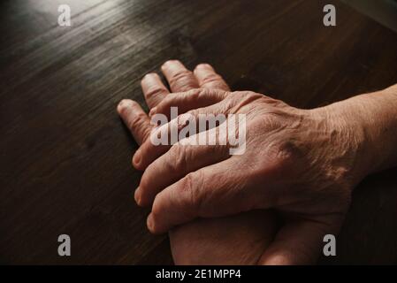 Hände des alten Mannes auf Holztisch. Hand übergeben. Weitwinkelansicht. Stockfoto