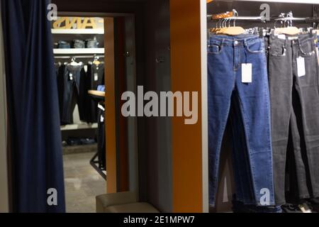 Reihe von aufgehängten blauen und schwarzen Jeans in einem Geschäft. Ankleidezimmer. Stockfoto