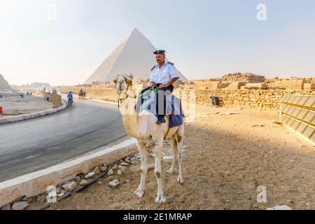 Lokaler Polizist montiert auf einem Kamel in der Giza Pyramid Complex (Giza Necropolis) vor der Pyramide von Khafre, Kairo, Ägypten Stockfoto