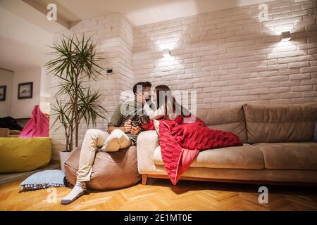 Paar trinken Tee und verbringen angenehmen Abend zu Hause. Frau küsst ihren Mann. Winterurlaub Konzept. Stockfoto