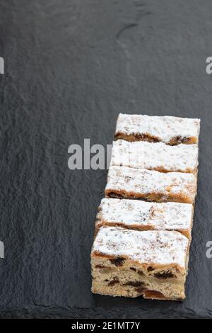 Weihnachtsstollen Scheiben mit Preiselbeere auf schwarzem Stein Hintergrund Stockfoto