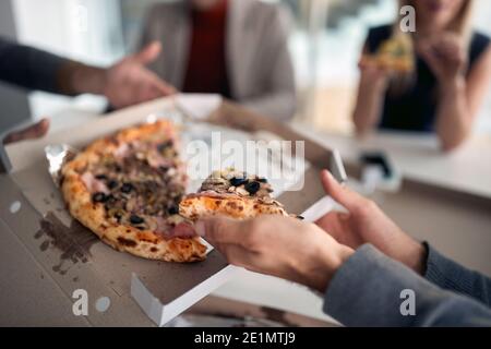 Pizza auf der heutigen Speisekarte in einer Pause in der Firmenkantine in angenehmer Atmosphäre. Menschen, Arbeit, Unternehmen, Geschäftskonzept. Stockfoto