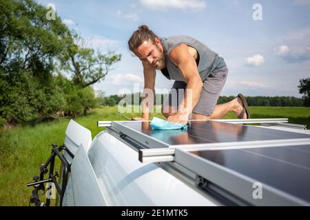 Mann, der ein Solarpanel auf einem Wohnwagen putzt Stockfoto