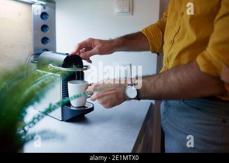 Ein junger Mann, der in entspannter Atmosphäre in der Küche Tee macht. Routine, Morgen Stockfoto