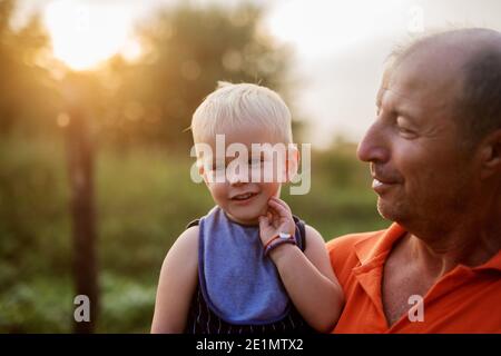 Nahaufnahme eines kleinen niedlichen blauäugigen Jungen in Großvätern Händen. Pure unendliche Liebe. Stockfoto