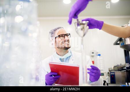 Fröhlicher Labormitarbeiter, der sich Notizen zu Testexperimenten gemacht hat. Stockfoto