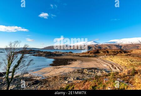 SCHOTTLAND WESTKÜSTE HIGHLANDS KINTAIL SANDAIG BAY UND INSELN DIE SANDSTRAND IN SONNENLICHT BEI EBBE SCHNEE AUF DER BERGE VON SKYE Stockfoto