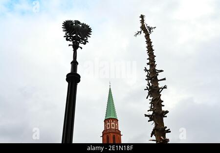 08. Januar 2021, Hessen, Frankfurt/Main: Der Stamm des Frankfurter Weihnachtsbaums (r), dessen Äste abgesägt sind, steht neben einer Stele mit dem Adlerwappen (l) und dem Turm der Alten Nikolaikirche. Die aus Österreich stammende Fichte Bertl steht seit dem 19. November 2020 auf dem Römerberg. Foto: Arne Dedert/dpa Stockfoto