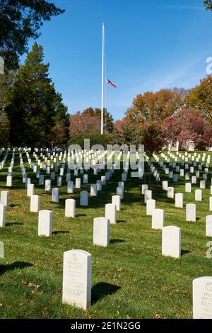 Auf dem Arlington National Cemetery in der Nähe von Washington DC fliegt eine Fahne über Reihen identischer Gräber. Stockfoto