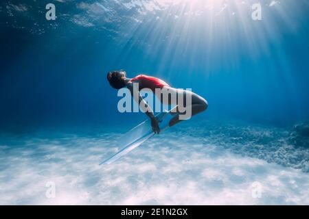 Attraktive Frau Freitaucher mit weißen Flossen posiert unter Wasser im tropischen Meer. Stockfoto