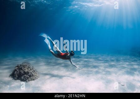 Attraktive Frau Freitaucher mit weißen Flossen posiert unter Wasser im tropischen Meer. Stockfoto