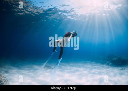 Attraktive Frau Freitaucher mit weißen Flossen posiert unter Wasser im tropischen Meer. Stockfoto
