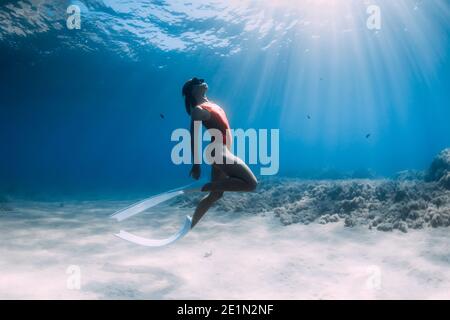 Attraktive Frau Freitaucher mit weißen Flossen posiert unter Wasser im tropischen Meer. Stockfoto