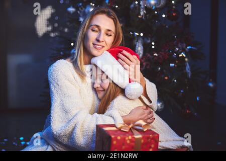 Glückliche Mutter umarmt geliebte Tochter zu Weihnachten Stockfoto