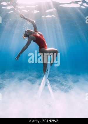 Attraktive Frau Freitaucher mit weißen Flossen posiert unter Wasser im tropischen Meer. Stockfoto