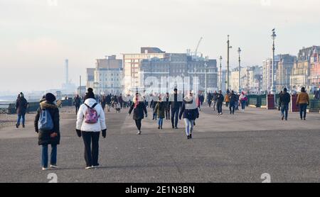 Brighton UK 8. Januar 2021 - Menschen gehen an einem kalten, aber sonnigen Nachmittag entlang der Küste von Hove, da die COVID-19-Sperrbeschränkungen in England weiter bestehen : Credit Simon Dack / Alamy Live News Stockfoto