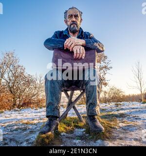 Vorderansicht der sitzenden Figur von Sean Henry. Große Skulptur in einem schneebedeckten Yorkshire Scuplture Park. Stockfoto