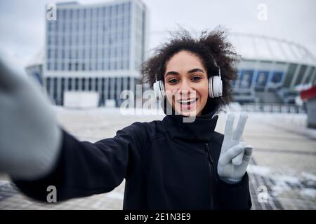 Frau zeigt ein V-Zeichen während der Aufnahme eines Fotos Stockfoto