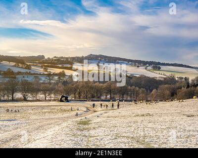 Zwei Große Formen. Von Henry Moor, zusammen mit Schafen und Besuchern in einem schneebedeckten Yorkshire Sculpture Park. VEREINIGTES KÖNIGREICH. Stockfoto