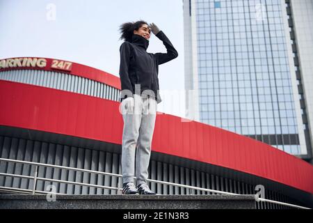 Frau, die gerade steht und ihre Augen mit einer Handfläche abschirmt Stockfoto