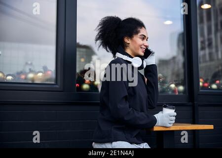 Fröhliches Telefongespräch von einer Frau, die Kaffee trinkt Stockfoto