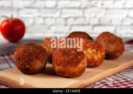 Köstliche heiße italienische arancini - Reisbällchen gefüllt mit Käse Auf einem Brett auf einem alten Holztisch Stockfoto