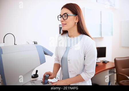 Arzt mit Joystick eines Autorefraktors Stockfoto