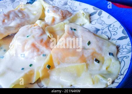 Teller mit Eiernudeln, Ravioli, gefüllt mit Kürbisfüllung und Wurst, gekrönt mit Butter und Salbei, für das Party-Mittagessen Stockfoto