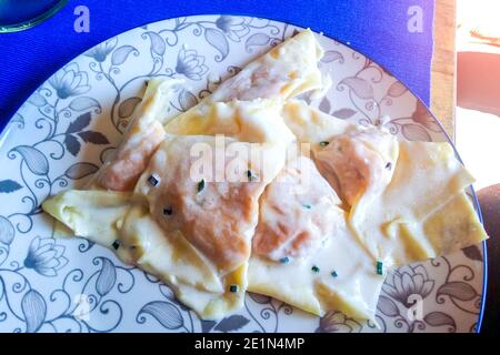 Teller mit Eiernudeln, Ravioli, gefüllt mit Kürbisfüllung und Wurst, gekrönt mit Butter und Salbei, für das Party-Mittagessen Stockfoto