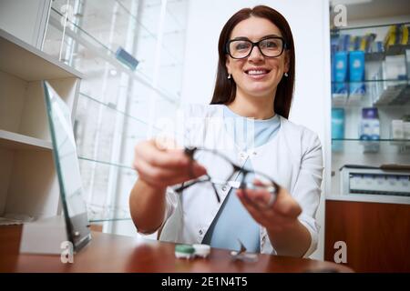 Ärztin, die einem Besucher eine Brille aushält Stockfoto