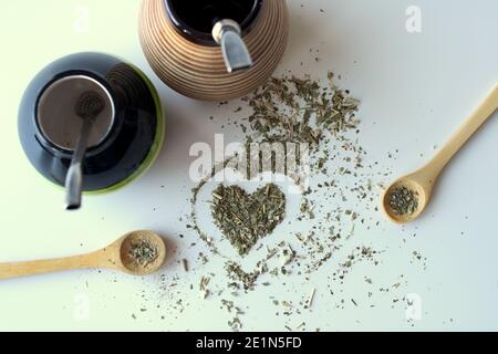 Zusammensetzung auf weißem Hintergrund - Bombilla, Kalabash, Löffel und Blätter von Tee Yerba Mate. Stockfoto