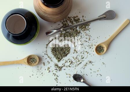 Zusammensetzung auf weißem Hintergrund - Bombilla, Kalabash, Löffel und Blätter von Tee Yerba Mate. Stockfoto