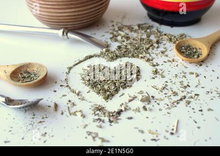 Zusammensetzung auf weißem Hintergrund - Bombilla, Kalabash, Löffel und Blätter von Tee Yerba Mate. Stockfoto