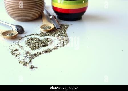 Zusammensetzung auf weißem Hintergrund - Bombilla, Kalabash, Löffel und Blätter von Tee Yerba Mate. Stockfoto