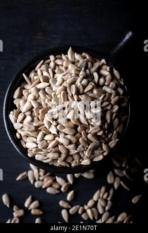 Geschälte Sonnenblumenkerne in Keramikschale auf dunklem Hintergrund. Stockfoto