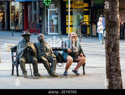 Die Statue von Slaveykovs und ein männlicher Tourist sitzt Die beliebte Bank in Slaveykov Platz in der Innenstadt von Sofia Bulgarien Ost Europa EU Stockfoto