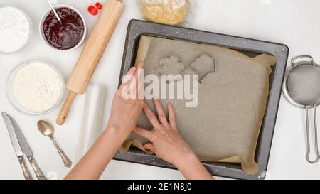 Frau Hände Linie Backform mit Pergamentpapier. Shortbread Cookie Rezept. Schritt für Schritt Backvorgang Stockfoto