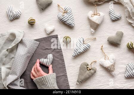 Handgemachte textile Herzen und Bälle auf Baumwollhintergrund. Stofftiere, Bälle und Kerze in neutralen Farben. Stockfoto