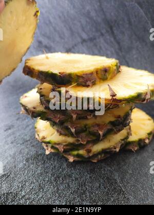 Geschnittene und gehackte Ananas auf dunklem Hintergrund Stockfoto