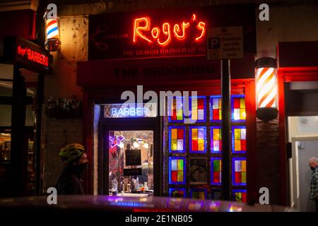 Blick auf die Straße bei Nacht eines Radfahrers, der an Rogers Demon Barbers Gebäude vorbeifährt, London, Großbritannien, Dezember 2020 Stockfoto