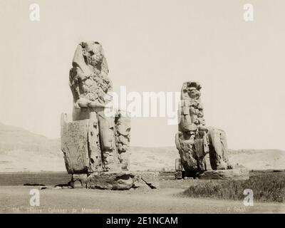 19. Jahrhundert Vintage-Foto: Theben, Ägypten, die Kolossi von Memnon. Die Kolossi von Memnon sind zwei massive Steinstatuen des Pharao Amenhotep III, der in Ägypten während der achtzehnten Dynastie von Ägypten regierte. Seit 1350 v. Chr. stehen sie in der Nekropole Theban, westlich des Nils von der modernen Stadt Luxor. um 1880. Stockfoto