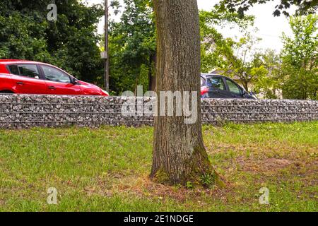 Trennung der Straße vom Parkgelände. Ein Fragment eines Zauns aus Gabionen. Stockfoto