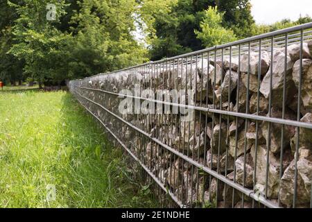 Trennung der Straße vom Parkgelände. Ein Fragment eines Zauns aus Gabionen. Stockfoto