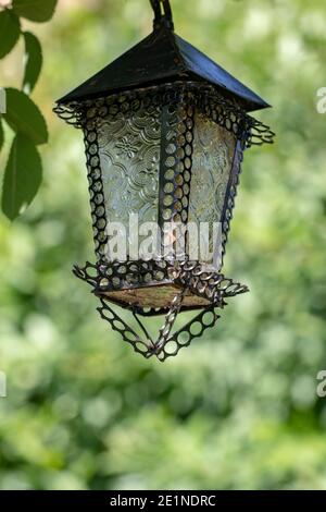 Selektive Konzentration auf eine schöne alte Laterne im Freien an einem sonnigen Sommertag vor natürlichem grünen Hintergrund. Makro. Stockfoto