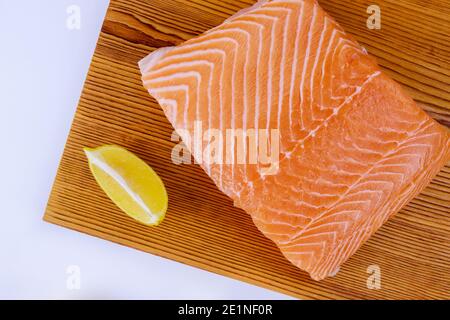 Lachs frisches Filet ein köstliches Fischfleisch und Zitrone mit Holzschneidebrett auf isoliertem weißem Hintergrund Stockfoto