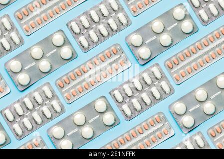 Geometrisches Muster mit Blister mit weißen Tabletten und Schmerzmitteln auf blauem Hintergrund. Konzept der Medizin Stockfoto