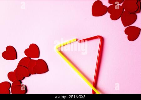 Herzen in der Ecke auf einem rosa Hintergrund mit zwei gelben und roten Trinkhalm verliebt. Valentinstag Stockfoto