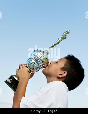 Foto von Kid Tennis Player Kissing Trophy Stockfoto